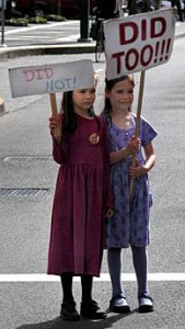 girls holding signs blaming each other