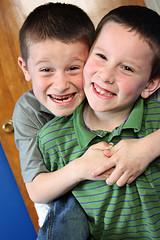 two boys hugging and smiling at camera