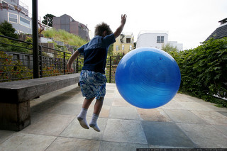 boy jumping in mid-air bouncing huge ball