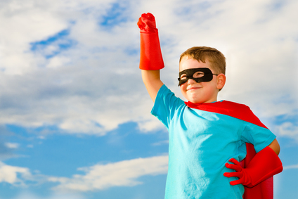 young boy in super hero costume striking heroic pose